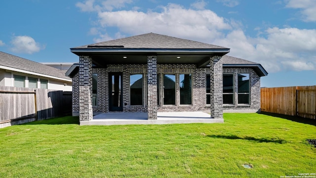 rear view of house featuring a lawn, brick siding, a fenced backyard, and a patio area