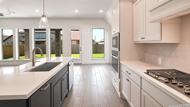 kitchen featuring backsplash, a sink, light countertops, white cabinets, and stainless steel appliances