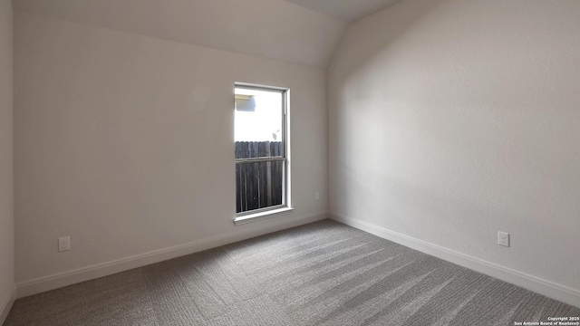spare room featuring baseboards, carpet flooring, and lofted ceiling