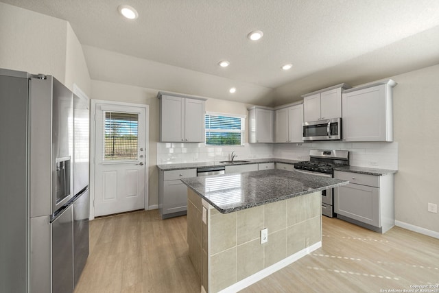 kitchen featuring appliances with stainless steel finishes, a center island, a wealth of natural light, and sink