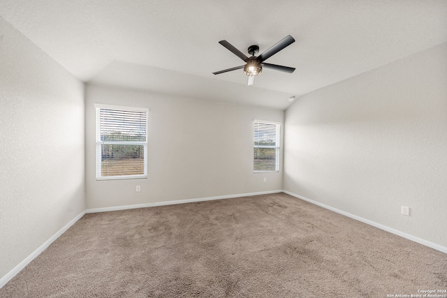 carpeted spare room featuring vaulted ceiling, ceiling fan, and a healthy amount of sunlight