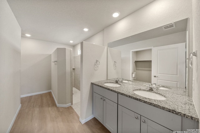 bathroom featuring vanity, wood-type flooring, a textured ceiling, and tiled shower