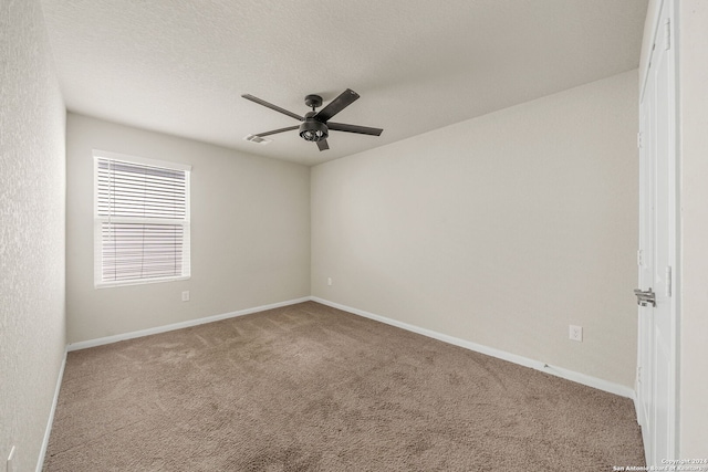 spare room featuring a textured ceiling, ceiling fan, and light carpet