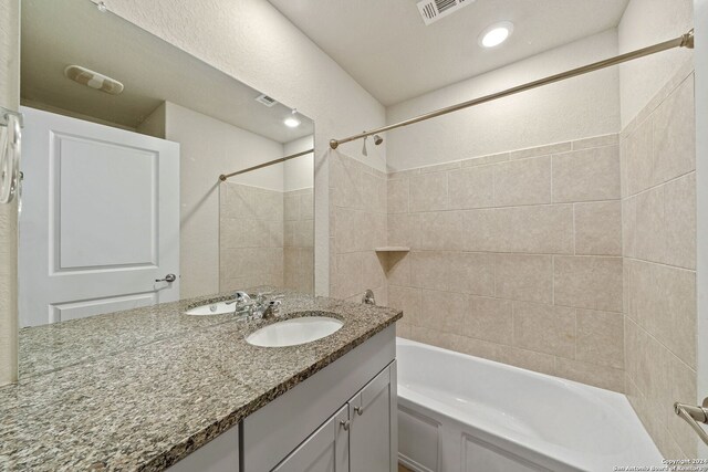 bathroom featuring vanity and tiled shower / bath