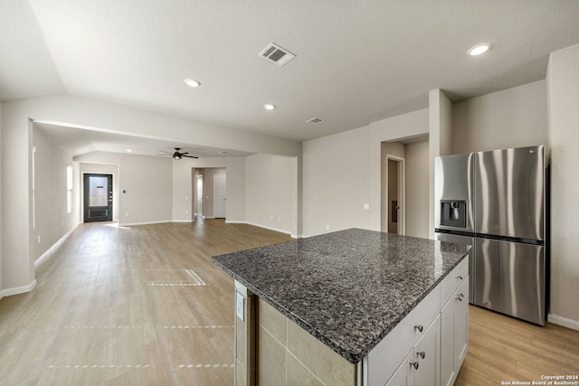 kitchen featuring white cabinetry, ceiling fan, stainless steel fridge, vaulted ceiling, and a kitchen island