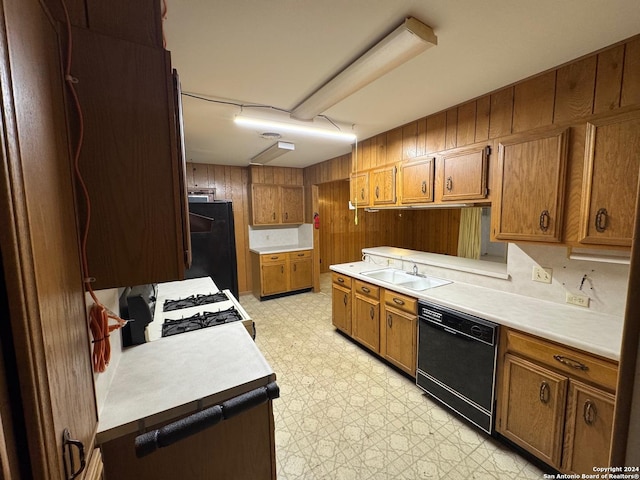 kitchen with black appliances, wood walls, and sink