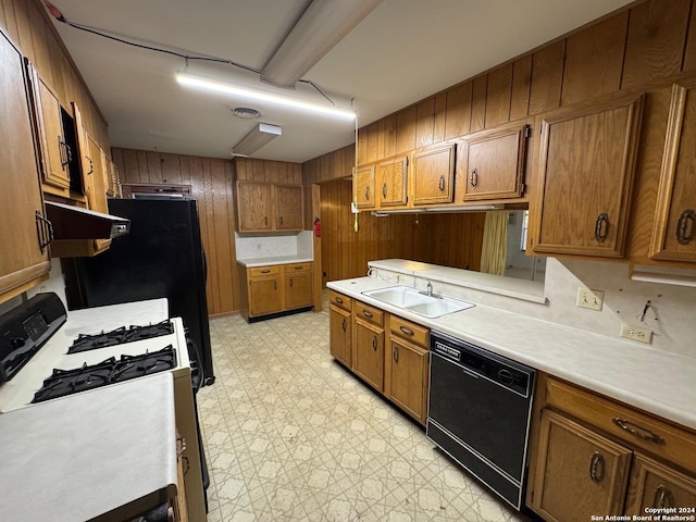 kitchen with sink, black dishwasher, wooden walls, and gas range gas stove