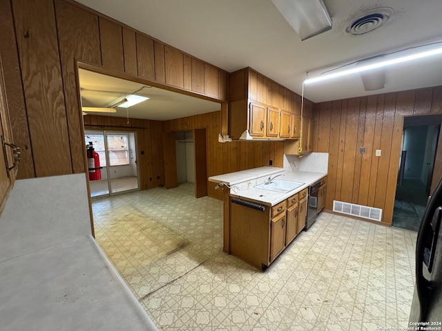 kitchen with dishwasher, sink, and wood walls