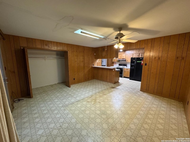 kitchen with wooden walls, ceiling fan, range with electric stovetop, black fridge with ice dispenser, and kitchen peninsula