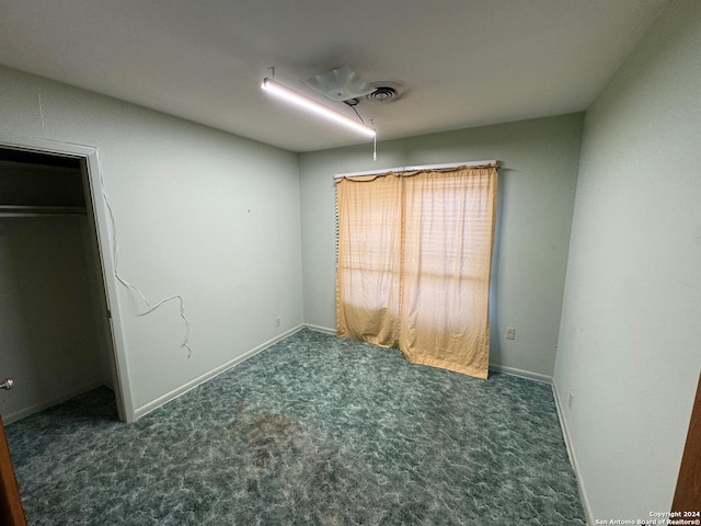 unfurnished bedroom featuring dark carpet and a closet