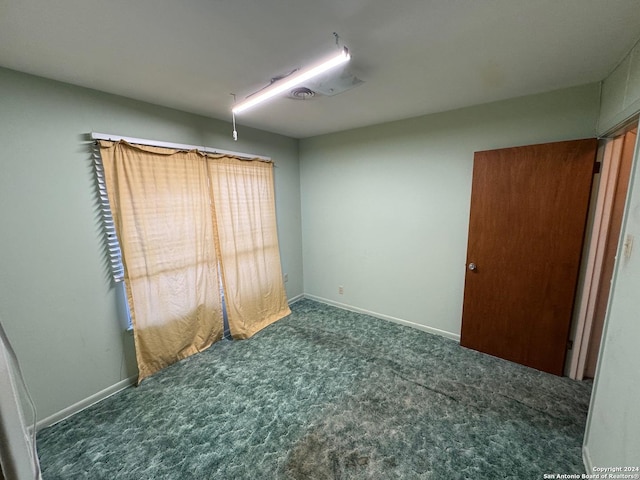 unfurnished room featuring dark carpet