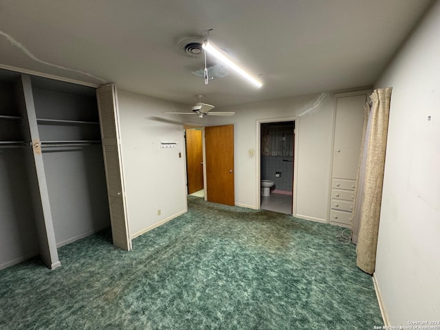 unfurnished bedroom with ceiling fan, ensuite bathroom, and dark colored carpet