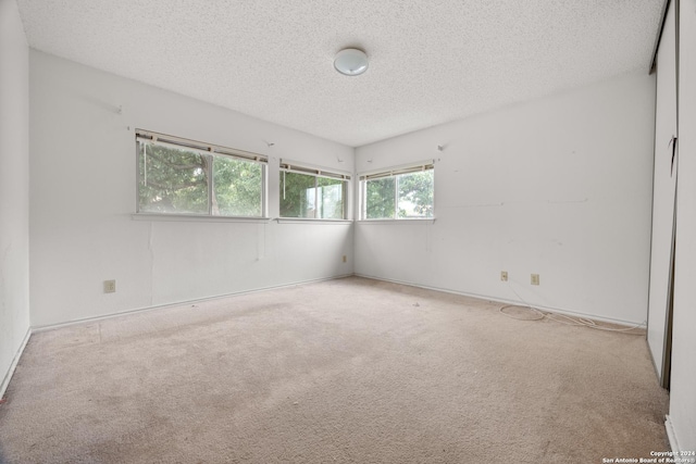 carpeted empty room featuring a textured ceiling