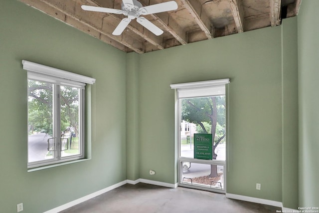 unfurnished room with ceiling fan, plenty of natural light, and concrete flooring