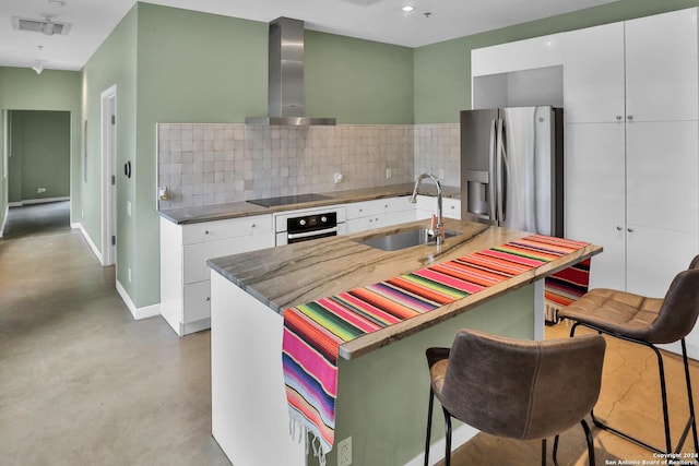 kitchen with stainless steel refrigerator with ice dispenser, white oven, sink, wall chimney range hood, and white cabinets