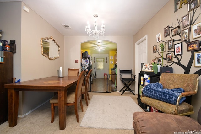 carpeted dining room featuring ceiling fan with notable chandelier