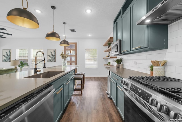 kitchen with pendant lighting, wall chimney range hood, sink, dark hardwood / wood-style floors, and stainless steel appliances