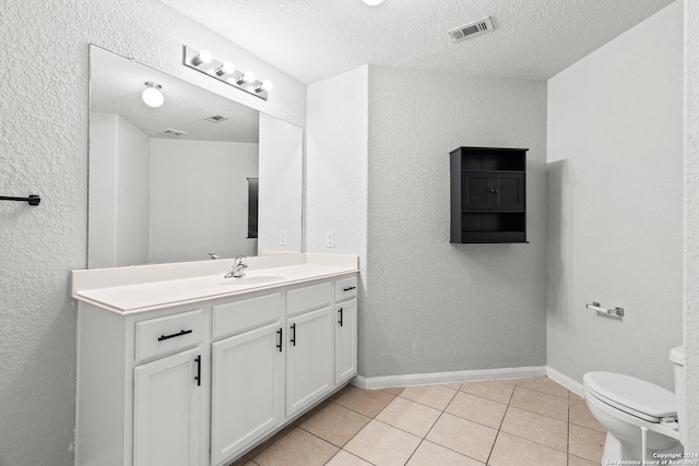 bathroom featuring tile patterned flooring, vanity, toilet, and a textured ceiling