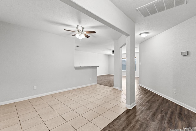 unfurnished living room featuring ceiling fan, light hardwood / wood-style floors, and a textured ceiling