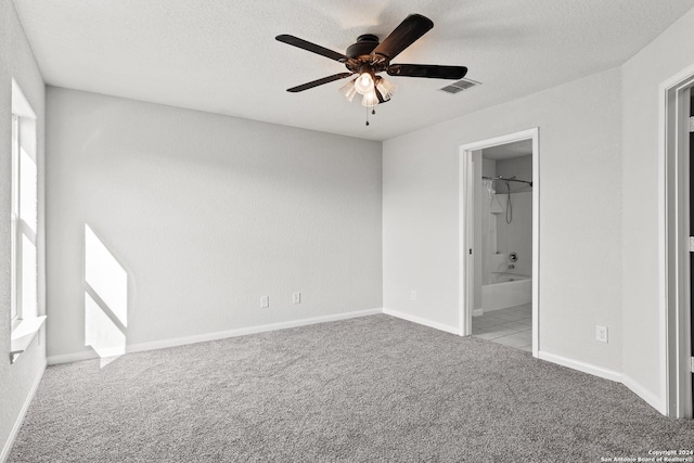 unfurnished bedroom featuring connected bathroom, ceiling fan, a walk in closet, light carpet, and a closet