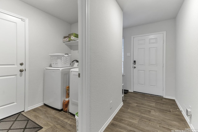 clothes washing area with separate washer and dryer and wood-type flooring