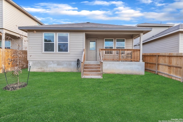 rear view of property featuring covered porch and a yard