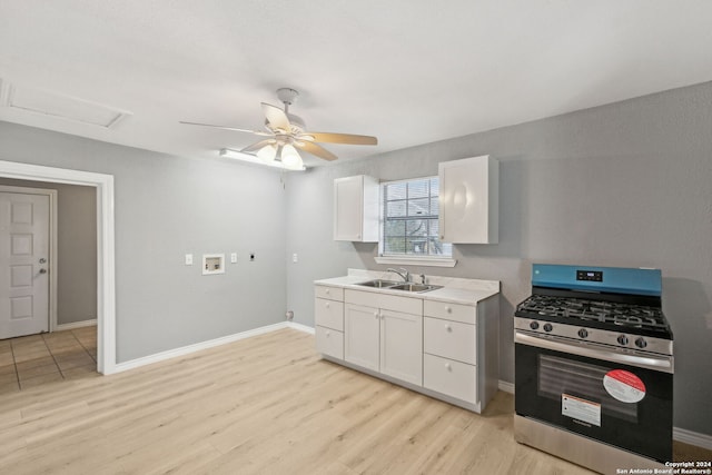 kitchen featuring white cabinets, light wood-type flooring, stainless steel gas range oven, and sink