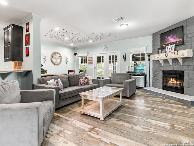 living room with crown molding, a fireplace, wood-type flooring, and french doors