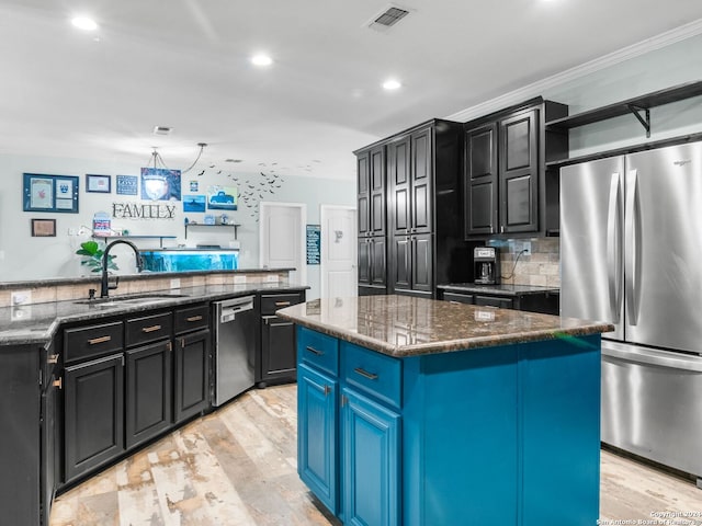 kitchen with dark stone countertops, sink, a center island, and appliances with stainless steel finishes