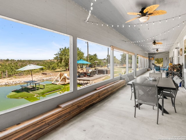 sunroom / solarium featuring ceiling fan and a water view