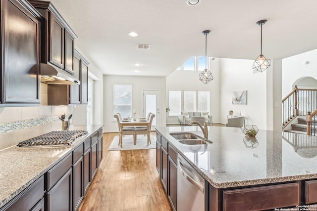 kitchen with sink, stainless steel appliances, light hardwood / wood-style floors, decorative light fixtures, and dark brown cabinets