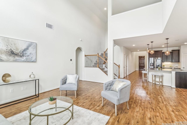 living room featuring sink, a high ceiling, and light wood-type flooring