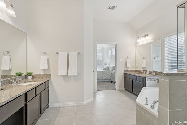 bathroom with tile patterned floors, vanity, lofted ceiling, and tiled bath