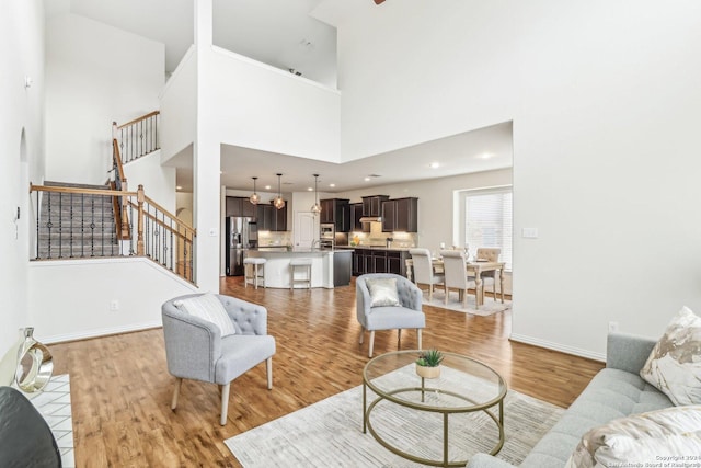 living room featuring light wood-type flooring and a towering ceiling