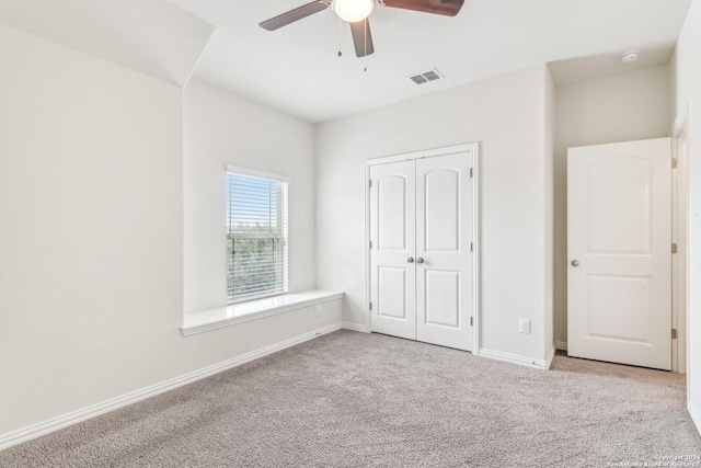 unfurnished bedroom with a closet, light colored carpet, and ceiling fan