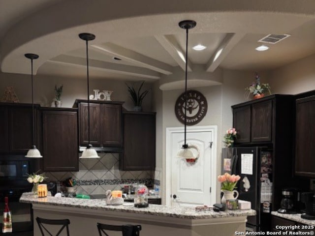 kitchen featuring black appliances, decorative light fixtures, decorative backsplash, light stone countertops, and dark brown cabinets