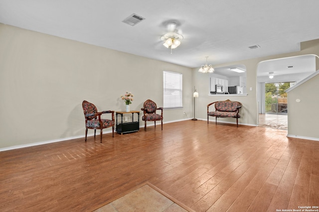 sitting room featuring wood-type flooring, ceiling fan with notable chandelier, and a wealth of natural light