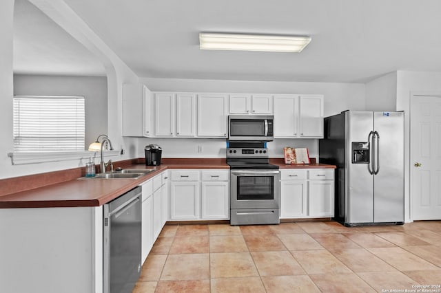 kitchen featuring white cabinetry, sink, light tile patterned flooring, and stainless steel appliances