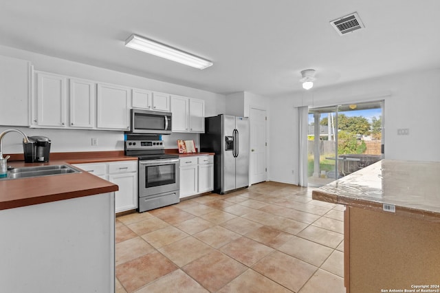 kitchen with white cabinetry, sink, light tile patterned floors, and stainless steel appliances