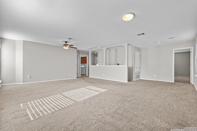 unfurnished living room with light carpet, ceiling fan, and washer / dryer