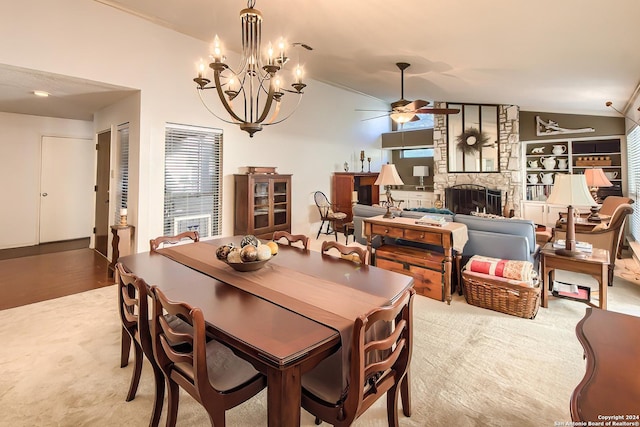 dining space featuring a fireplace, ceiling fan with notable chandelier, vaulted ceiling, and light wood-type flooring