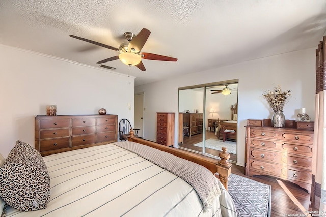 bedroom featuring ceiling fan, a closet, wood-type flooring, and a textured ceiling