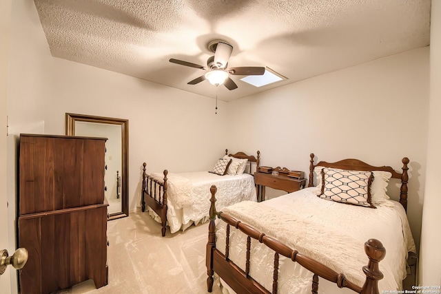 carpeted bedroom with ceiling fan, a textured ceiling, and a skylight