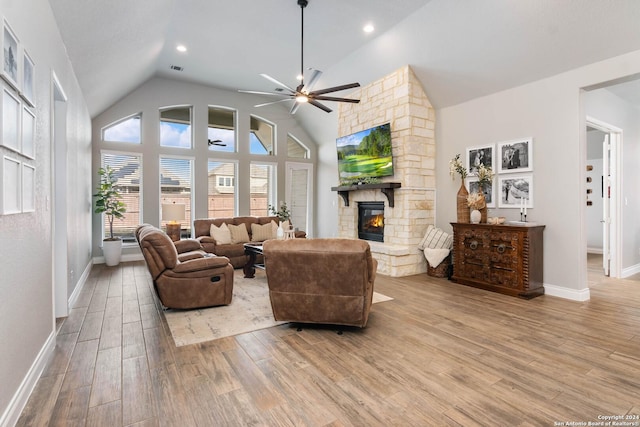 living room featuring ceiling fan, light wood-type flooring, a fireplace, and high vaulted ceiling