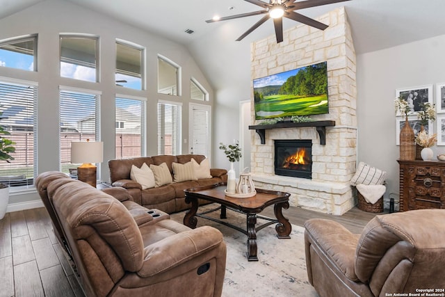 living room featuring a stone fireplace, ceiling fan, light hardwood / wood-style flooring, and lofted ceiling