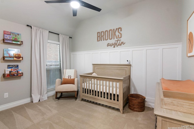 carpeted bedroom with ceiling fan, a nursery area, and vaulted ceiling