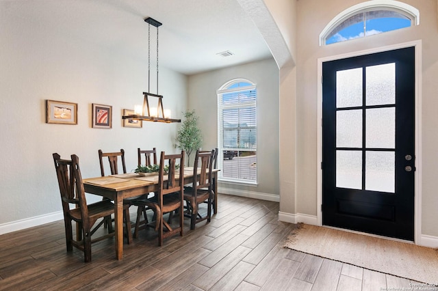 dining space with dark hardwood / wood-style flooring and an inviting chandelier