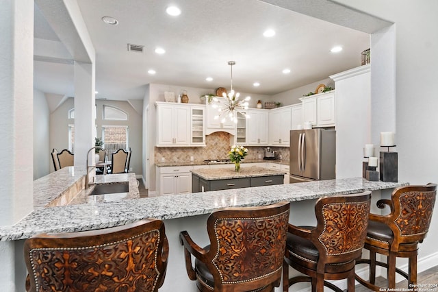 kitchen featuring white cabinetry, sink, stainless steel appliances, light stone counters, and kitchen peninsula