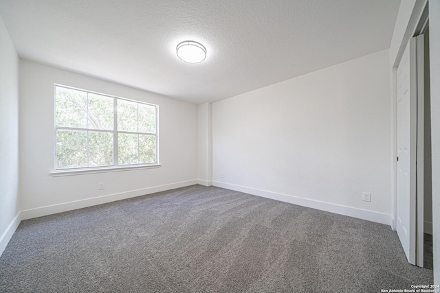 unfurnished room featuring dark colored carpet and a textured ceiling