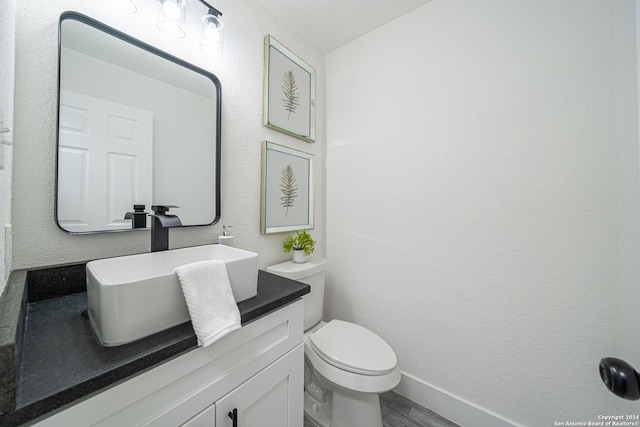 bathroom with hardwood / wood-style floors, vanity, and toilet